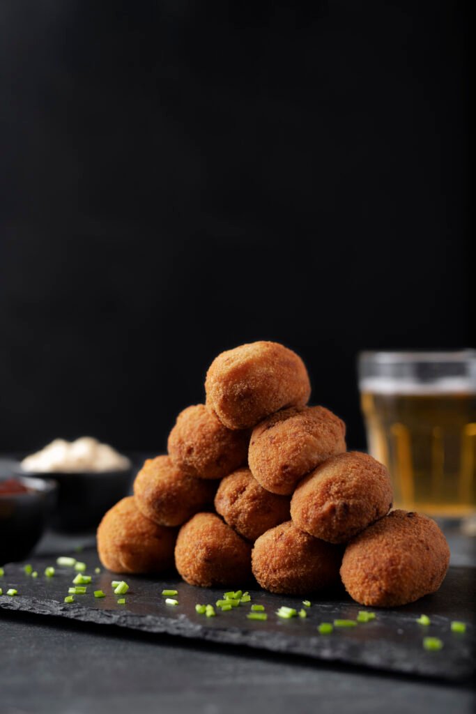 comida que contiene croquetas con perejil y un vaso de cerveza comida que contiene croquetas con perejil y un vaso de cerveza